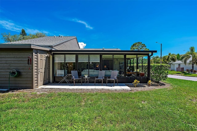 rear view of property featuring a patio, a lawn, and a sunroom