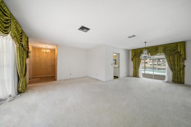 empty room with light carpet and a notable chandelier