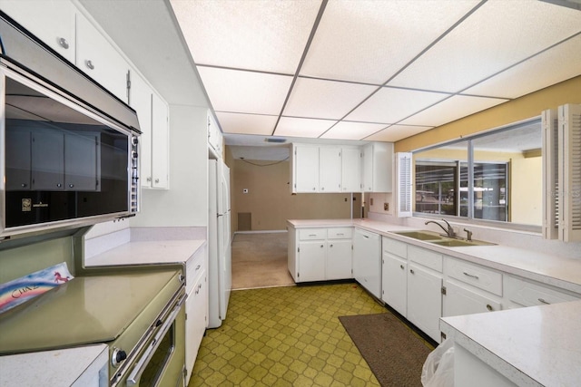 kitchen with appliances with stainless steel finishes, white cabinetry, a drop ceiling, and sink