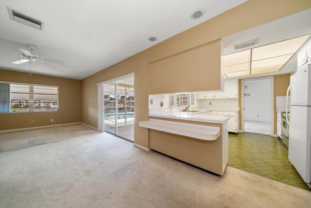 kitchen with kitchen peninsula, ceiling fan, sink, stainless steel range oven, and white fridge