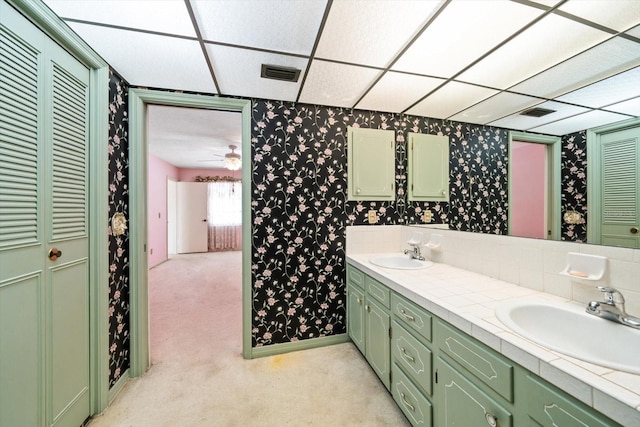 bathroom with vanity, a drop ceiling, and ceiling fan