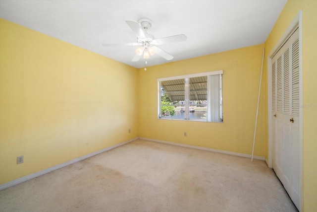 unfurnished bedroom featuring light colored carpet, a closet, and ceiling fan