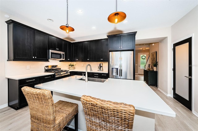 kitchen featuring sink, pendant lighting, a center island with sink, and appliances with stainless steel finishes