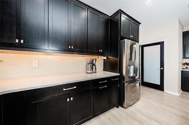 kitchen with stainless steel fridge with ice dispenser, light wood-type flooring, and tasteful backsplash