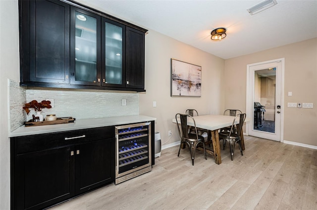 dining area with bar, light wood-type flooring, and wine cooler