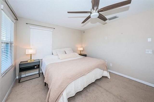 bedroom with multiple windows, ceiling fan, and light carpet