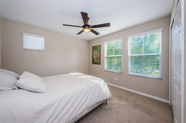 carpeted bedroom featuring ceiling fan and a closet