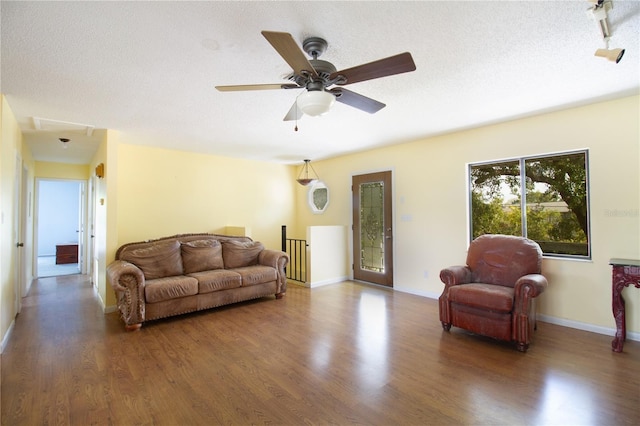 living room with ceiling fan, dark hardwood / wood-style flooring, and a textured ceiling