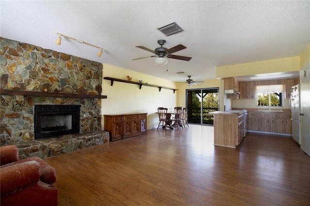 kitchen featuring a stone fireplace, a textured ceiling, dark hardwood / wood-style flooring, kitchen peninsula, and white fridge