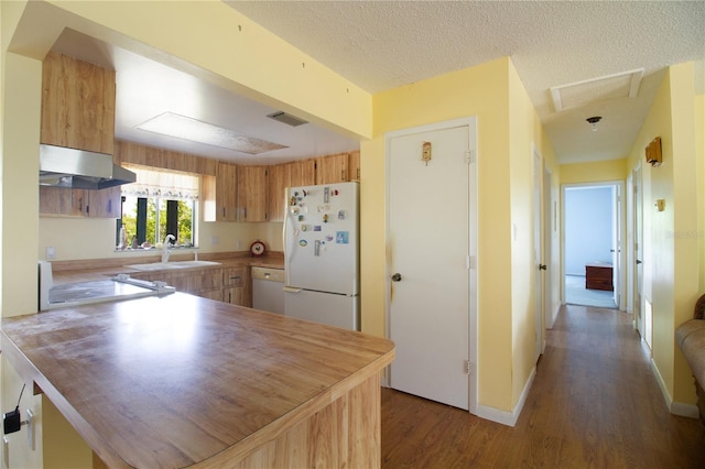 kitchen with dark wood-type flooring, sink, a textured ceiling, kitchen peninsula, and white appliances