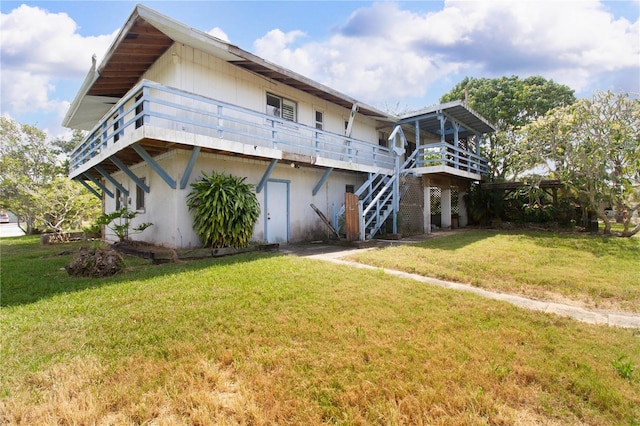 rear view of house featuring a wooden deck and a yard