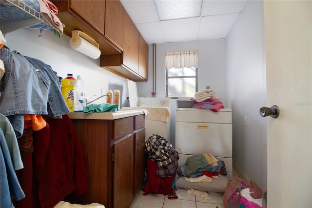 laundry area with cabinets, light tile patterned floors, and washing machine and clothes dryer