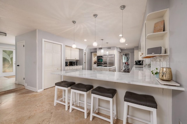 kitchen with pendant lighting, a kitchen breakfast bar, kitchen peninsula, appliances with stainless steel finishes, and white cabinetry