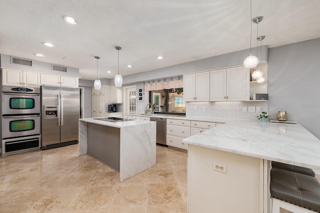 kitchen with kitchen peninsula, appliances with stainless steel finishes, a kitchen island, and pendant lighting