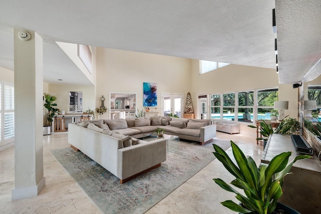 living room featuring french doors, a high ceiling, and a textured ceiling