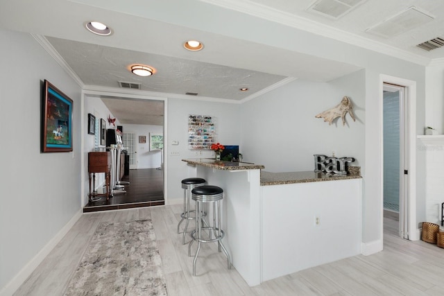 bar featuring stone countertops, light hardwood / wood-style floors, and ornamental molding