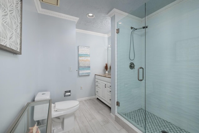 bathroom featuring a textured ceiling, toilet, vanity, a shower with shower door, and ornamental molding