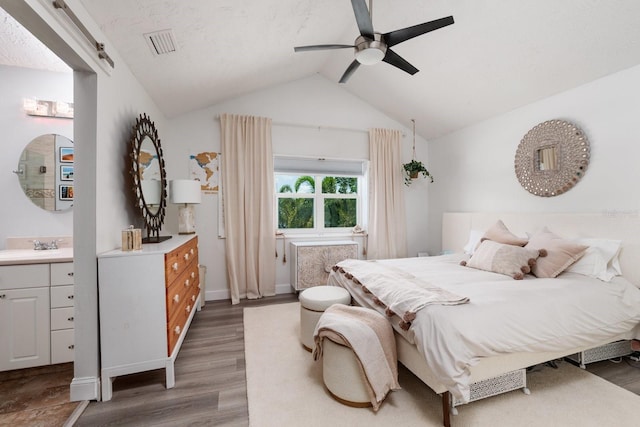 bedroom with sink, vaulted ceiling, ceiling fan, a barn door, and dark hardwood / wood-style flooring