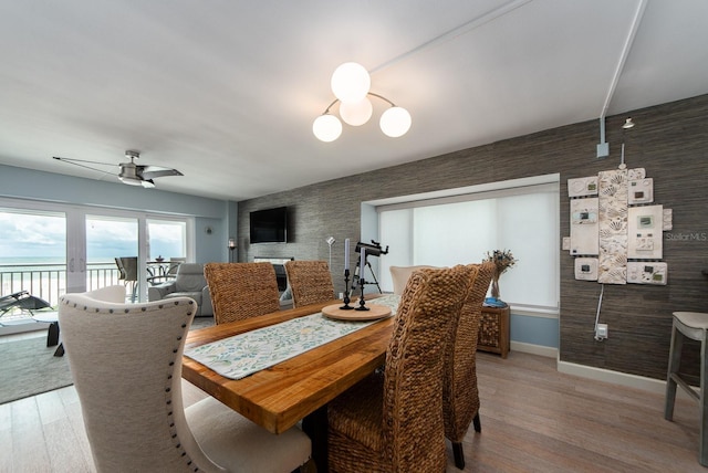 dining space with wood-type flooring, a water view, and ceiling fan