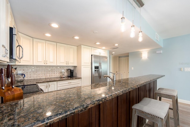 kitchen featuring decorative light fixtures, decorative backsplash, stainless steel appliances, and dark stone counters