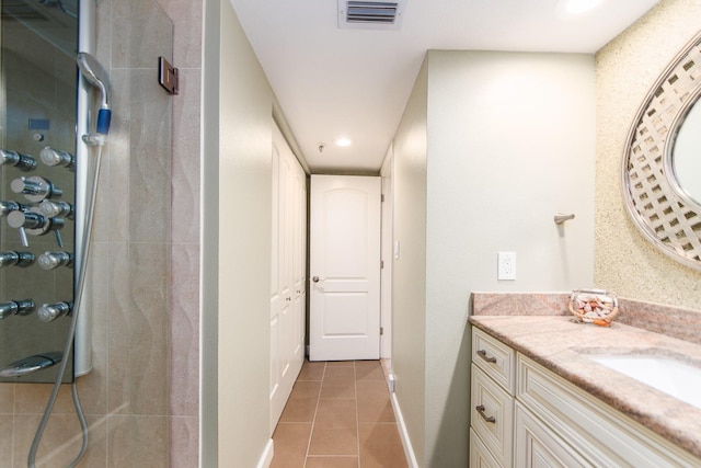 bathroom featuring a tile shower, vanity, and tile patterned floors