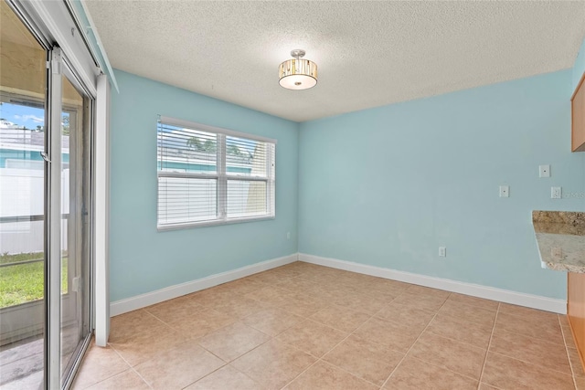 spare room featuring light tile patterned floors and a textured ceiling