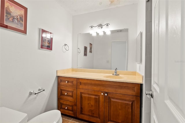 bathroom featuring tile patterned floors, toilet, a textured ceiling, and vanity