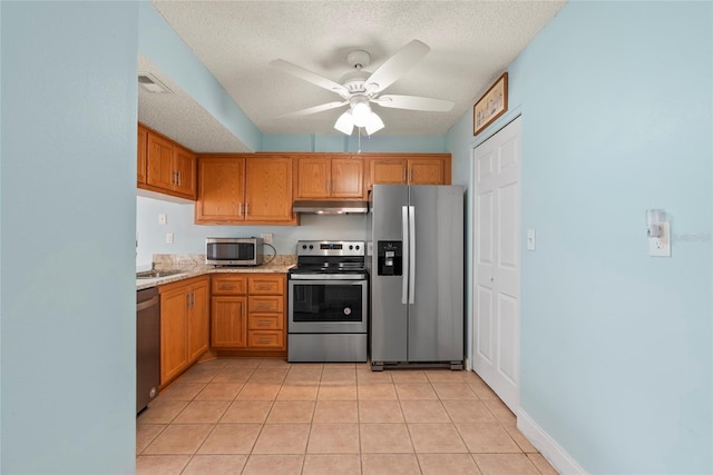 kitchen with stainless steel appliances, a textured ceiling, and light tile patterned floors