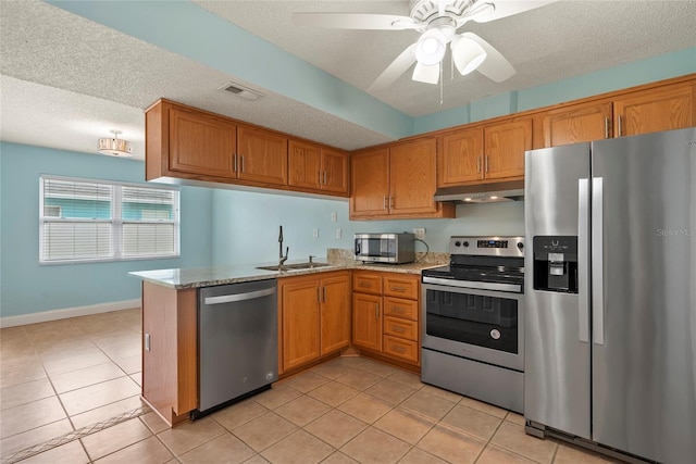 kitchen featuring appliances with stainless steel finishes, sink, light tile patterned floors, kitchen peninsula, and a textured ceiling