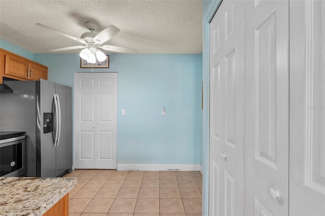 kitchen with ceiling fan, appliances with stainless steel finishes, light tile patterned floors, and a textured ceiling