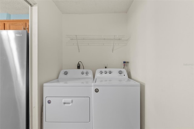 clothes washing area with washer and dryer and a textured ceiling