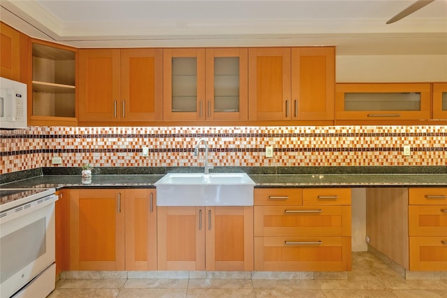 kitchen with tasteful backsplash, light tile patterned floors, white appliances, dark stone counters, and sink