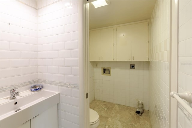 bathroom featuring sink, toilet, and tile walls