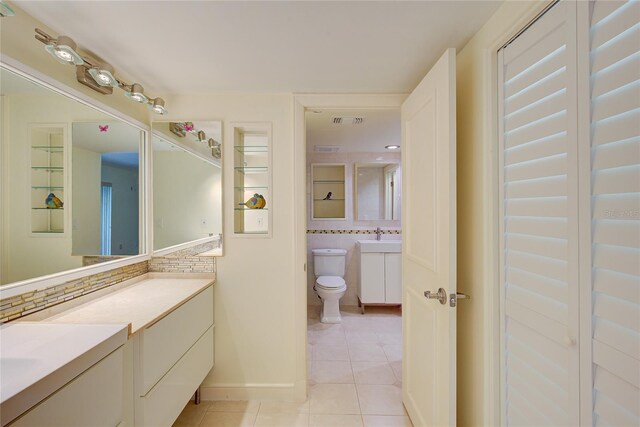 bathroom featuring vanity, tile patterned flooring, tasteful backsplash, and toilet