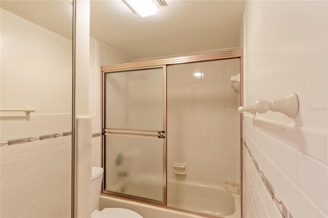 bathroom with bath / shower combo with glass door and toilet