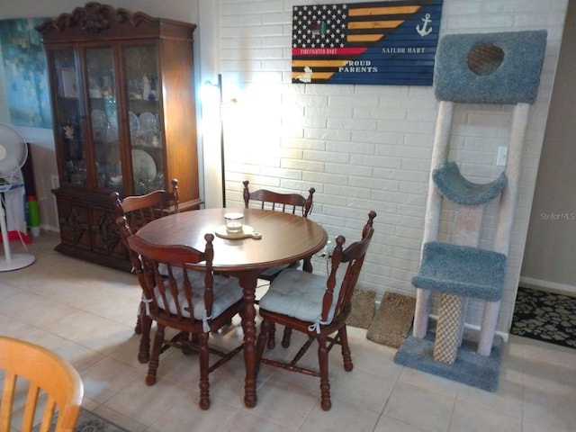 tiled dining room featuring brick wall