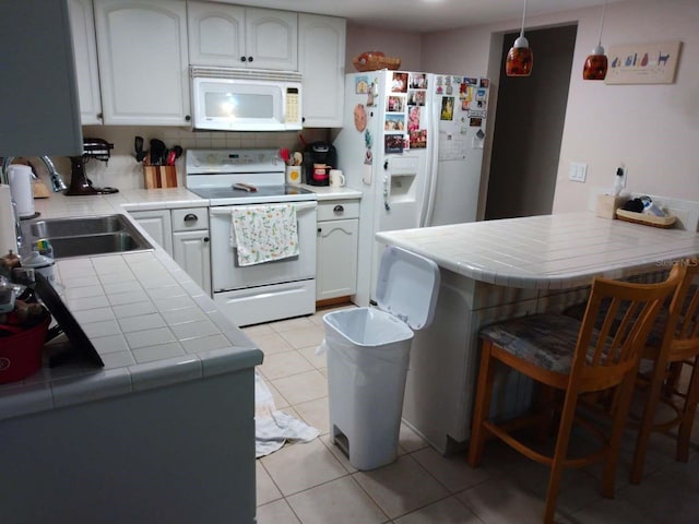 kitchen with white appliances, kitchen peninsula, hanging light fixtures, tile countertops, and sink