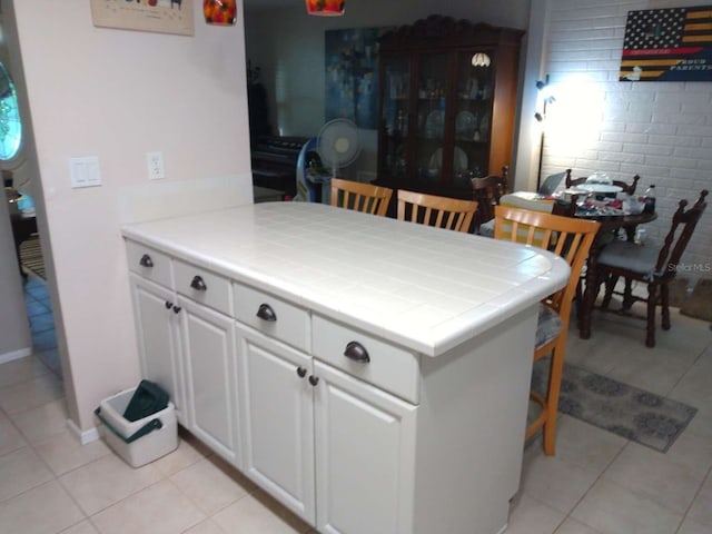 kitchen featuring tile countertops, light tile patterned floors, and white cabinets