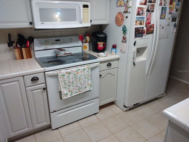 kitchen featuring tile counters, tasteful backsplash, white appliances, light tile patterned floors, and white cabinets