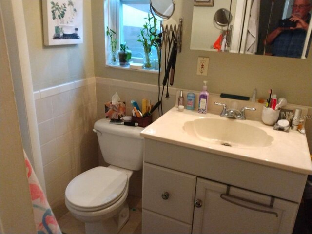 bathroom with vanity, tile walls, and toilet