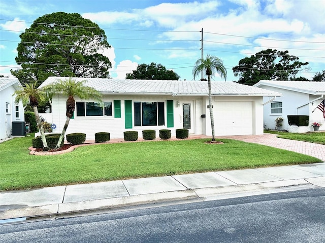 ranch-style home featuring cooling unit, a garage, and a front yard