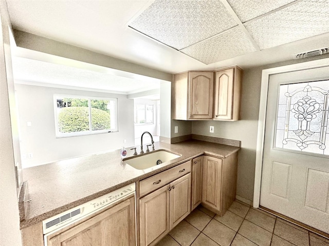 kitchen featuring light tile patterned flooring, light brown cabinetry, sink, dishwasher, and a drop ceiling