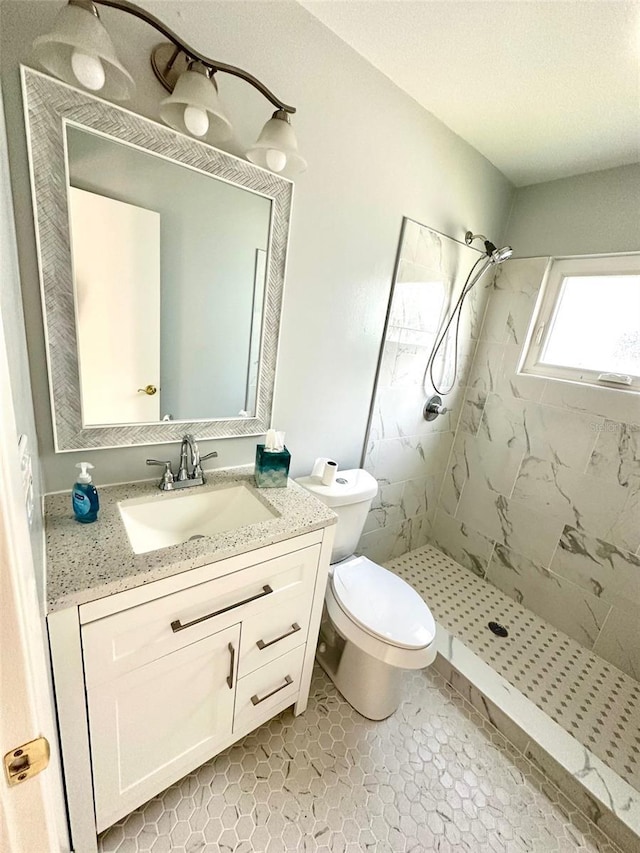 bathroom featuring tiled shower, vanity, toilet, and tile patterned flooring