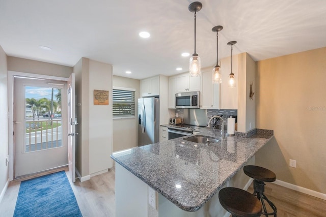 kitchen with tasteful backsplash, light hardwood / wood-style floors, appliances with stainless steel finishes, and kitchen peninsula