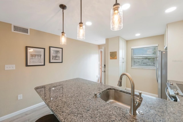 kitchen featuring hanging light fixtures, light wood-type flooring, sink, appliances with stainless steel finishes, and stone countertops