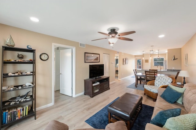 living room featuring sink, light wood-type flooring, and ceiling fan