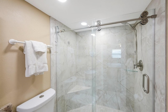 bathroom with a shower with shower door and toilet