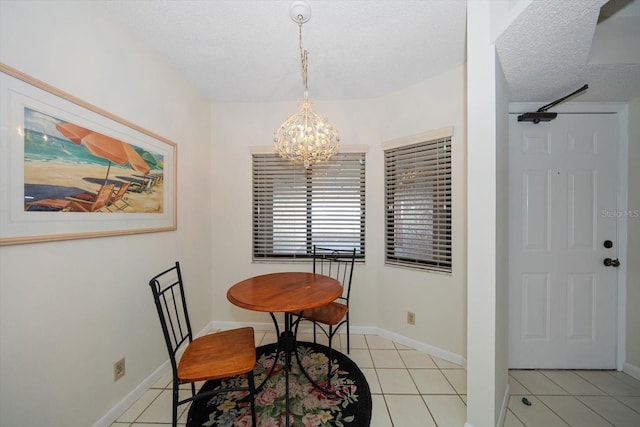 dining space with a textured ceiling, a notable chandelier, and light tile patterned floors