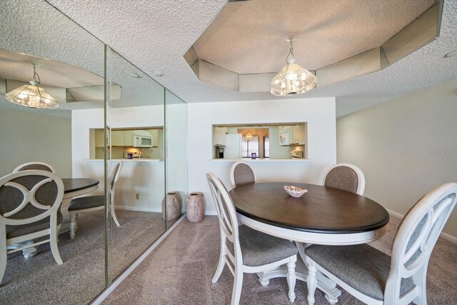 carpeted dining area featuring a tray ceiling, a notable chandelier, and a textured ceiling