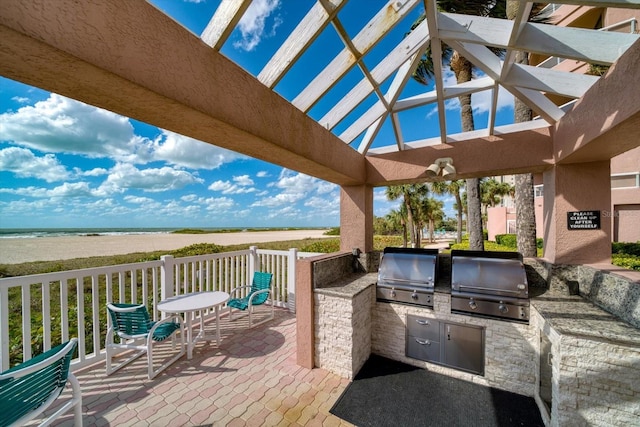 exterior space featuring a pergola, a water view, an outdoor kitchen, and area for grilling